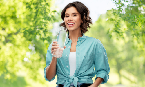 Smiling Woman Drinking Water from Glass Eco Bottle